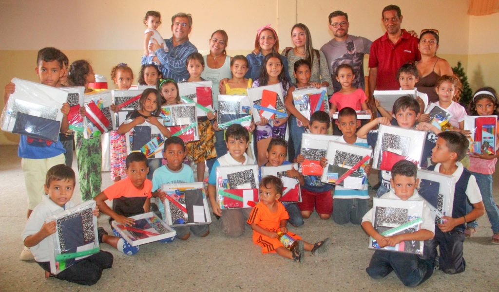 Children posing with donated school supplies