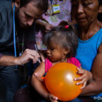 Baby with an orange balloon getting a shot